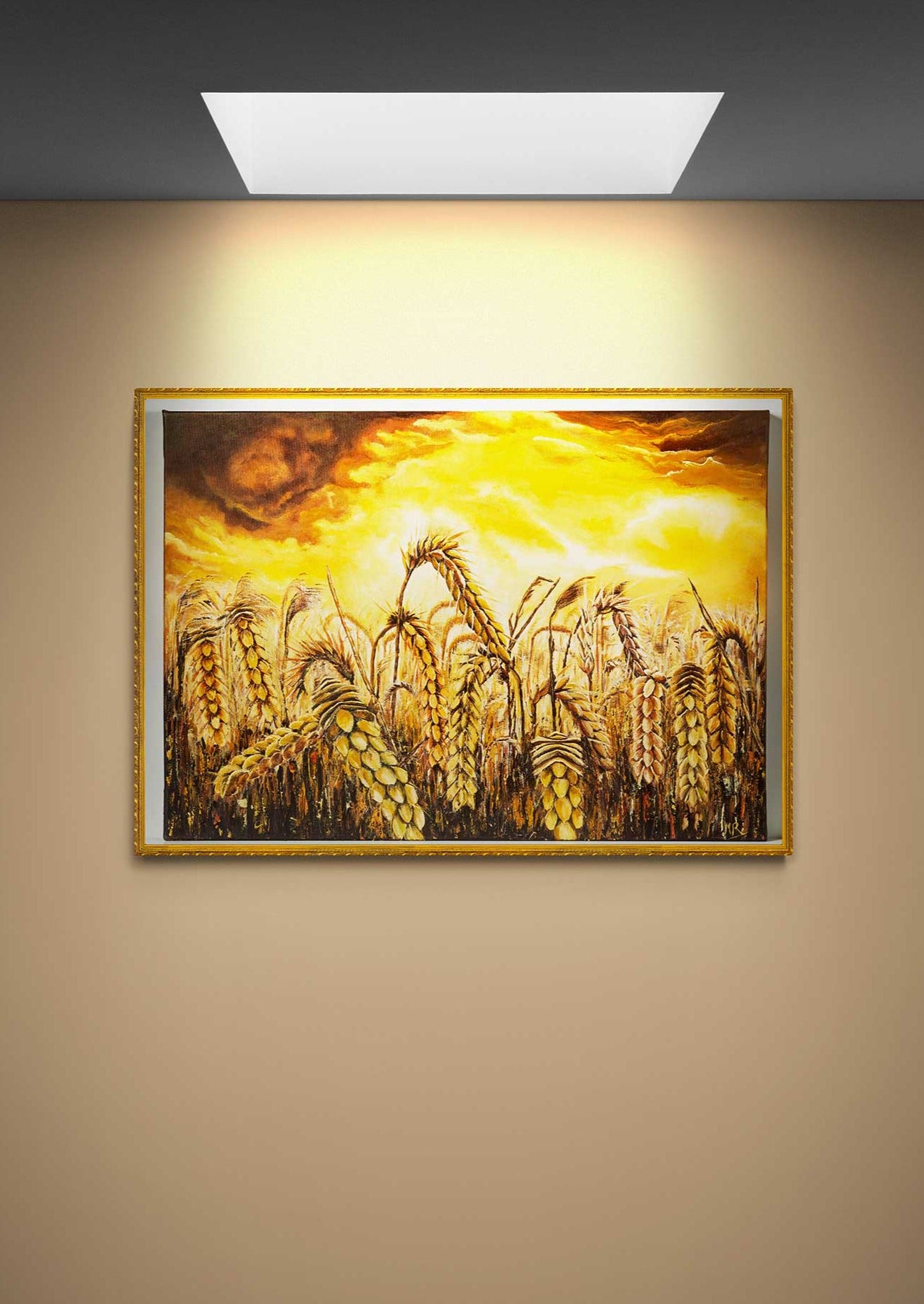 Wall Art Canvas Print Stormy Wheat Field with golden  colours and a sky brewing a  golden dark clouds and white light golden storm  stirring above. Framed in gold on a beige wall with direct sunlight above.