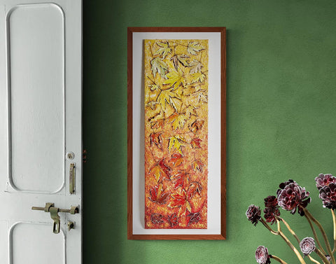 Canvas print wall art tumbling leaves of autumn.A long paining of tumbling maple leaves, staring at the top with light hints of green & yellos through to stronger yellows & golds to auburns to oranges, burnt oranges & reds through to stronger reds & mauve's, hung on a dinning room wall with a wooden frame.